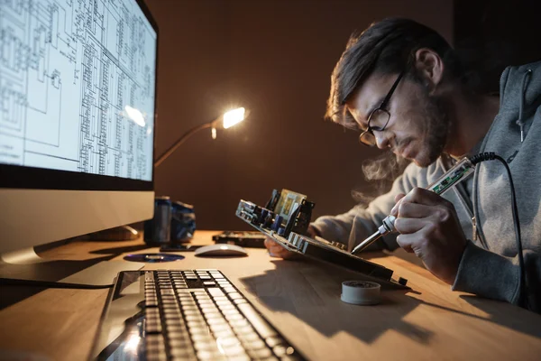 Homem focado reparando o motheboard com ferro de solda — Fotografia de Stock