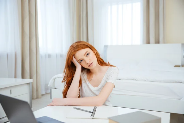 Рыжая женщина, сидящая за столом с домашним заданием — стоковое фото