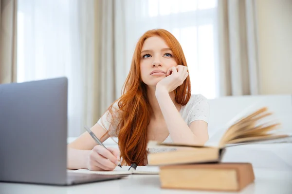 Mujer pensativa sentada a la mesa con su tarea — Foto de Stock