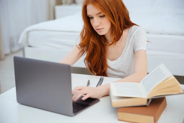 Woman using laptop computer while doing homework — Stock Photo, Image