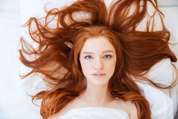 Femme avec de beaux cheveux rouges allongés dans le lit — Photo