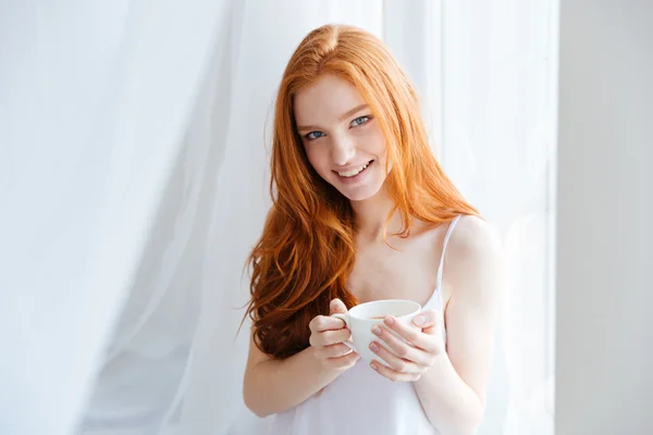 Redhead woman holding cup with tea at home — Stock Photo, Image