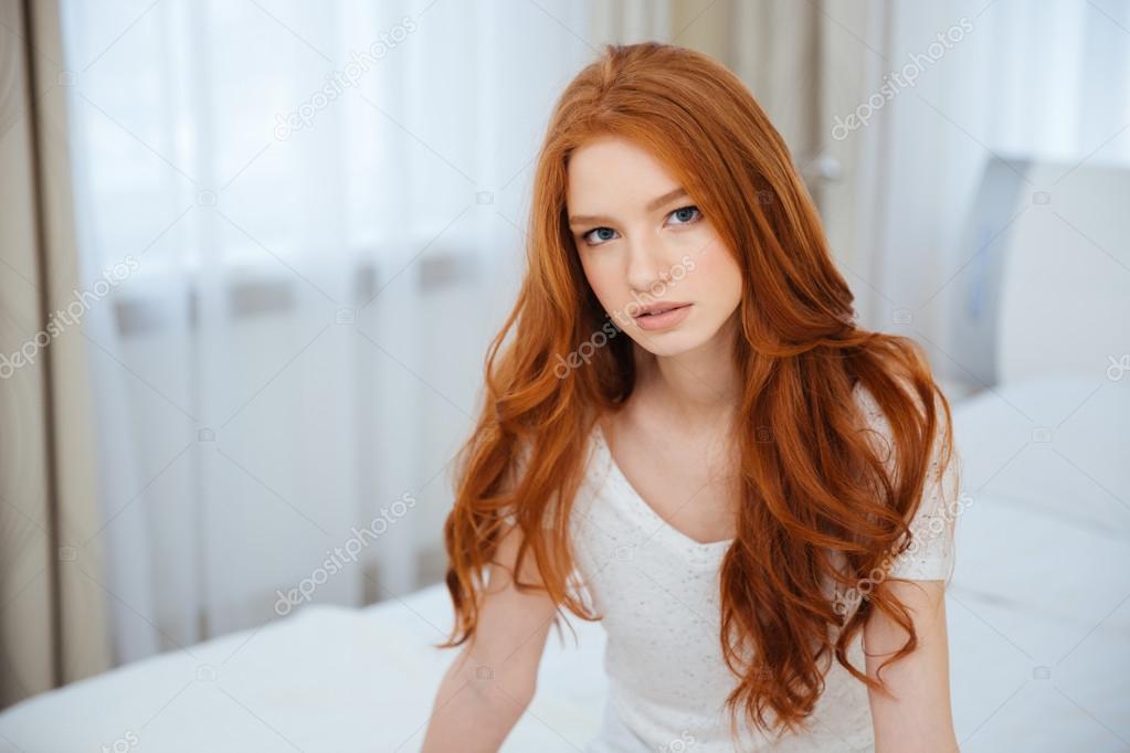 Redhead woman sitting on the bed at home