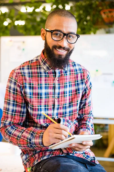 Man sitting on the table with notepad and pencil — Stock Photo, Image