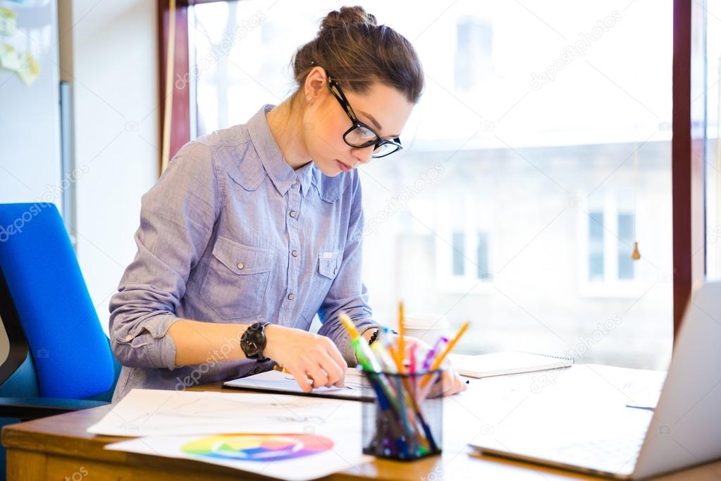 Concentrated woman fashion designer drawing sketches in office