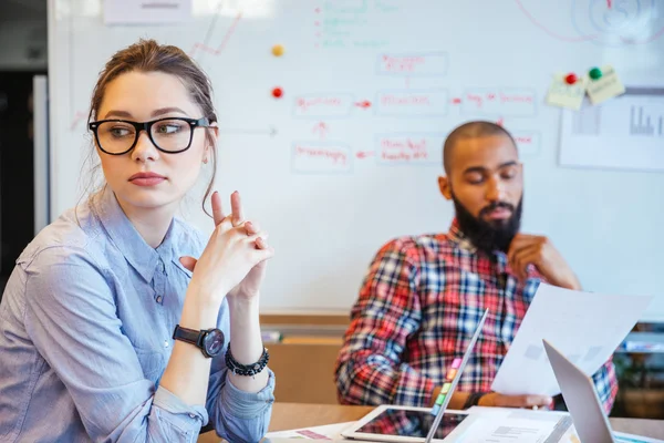 Pensive woman sitting and thinking while her male colleague reading — Stock Photo, Image