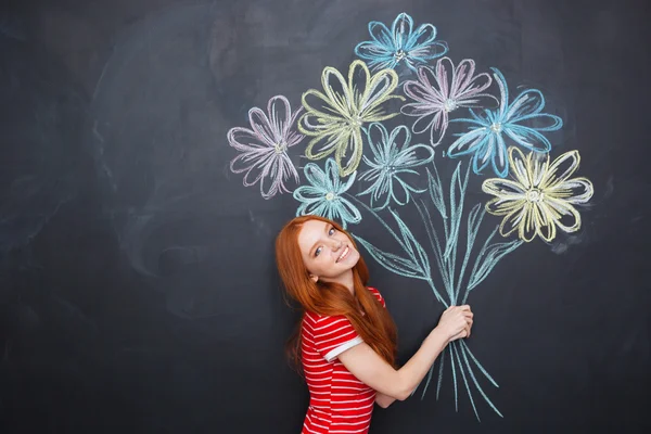 Mulher alegre posando com buquê de flores desenhado no fundo blackboard — Fotografia de Stock