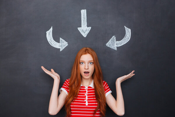 Wondered woman over blackboard with drawn arrows pointing on her