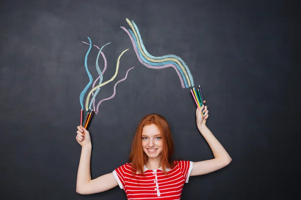 Cheerful woman standing and drawing on blackboard background — 图库照片