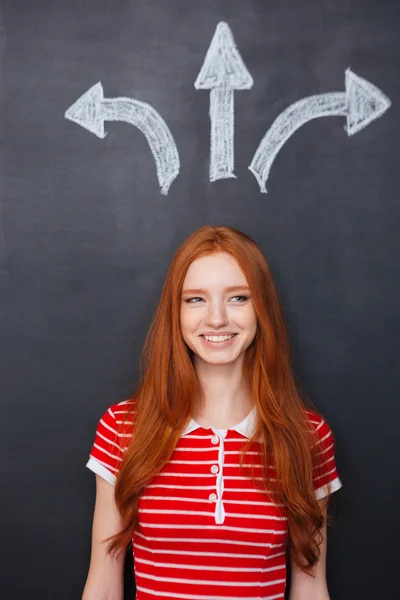 Fröhliche Frau trifft Entscheidung im Stehen über Kreidetafel-Hintergrund — Stockfoto