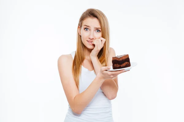 Mulher duvidosa sobre dieta pensando e segurando pedaço de bolo — Fotografia de Stock