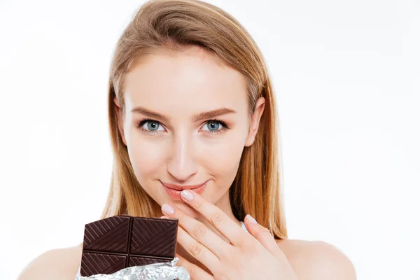Schöne lächelnde junge Frau, die eine Tafel Schokolade isst — Stockfoto