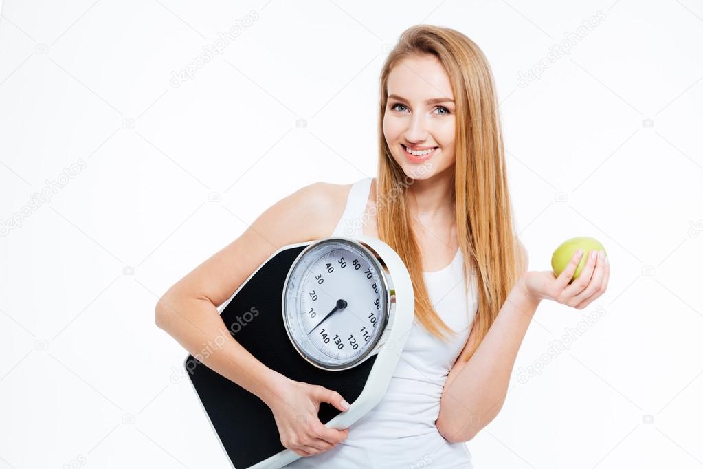 Cheerful beautiful  woman holding scales and green apple 