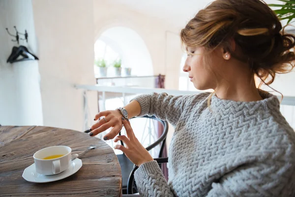 Woman looking on wrist watch in restaurant Stock Picture