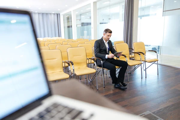 Uomo d'affari concentrato pensieroso utilizzando tablet in sala conferenze vuota — Foto Stock