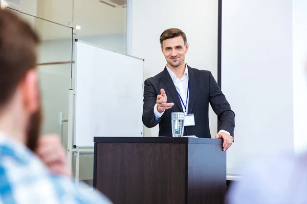 Un hombre de negocios sonriente parado en la tribuna en la sala de conferencias — Foto de Stock