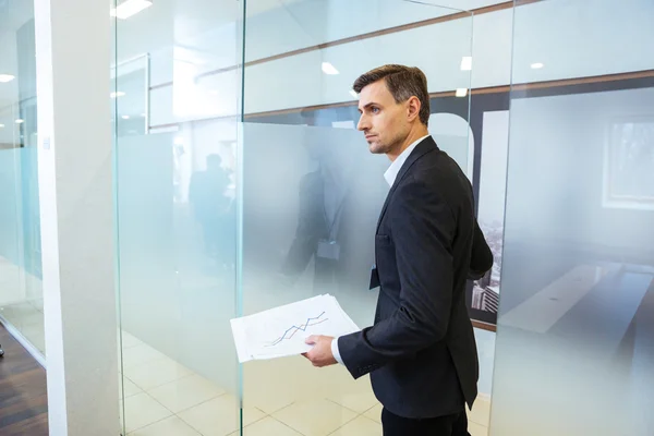 Confident businessman holding documents and entering the office — Stock Photo, Image