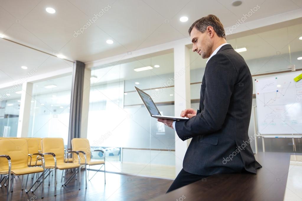 Focused serious businessman preparing for presentation using laptop 