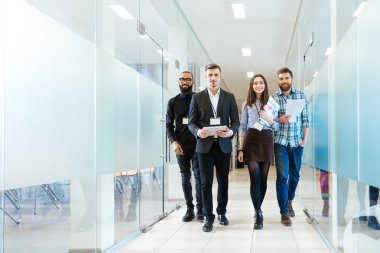 Group of happy young business people walking in office together clipart
