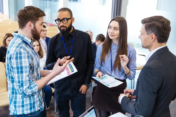 Confident business people standing and discussing financial report in office — Stock Photo, Image