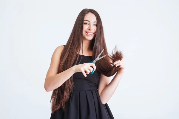 Mulher alegre cortando pontas de divisão de cabelo longo com tesoura — Fotografia de Stock
