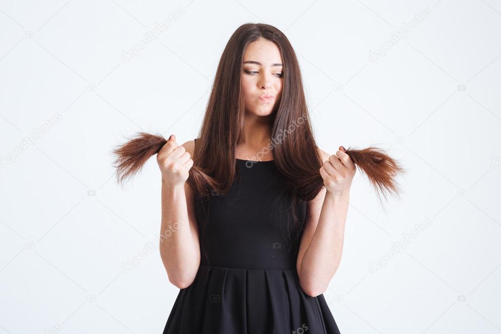 Upset beautiful woman looking on splitting ends of long hair 