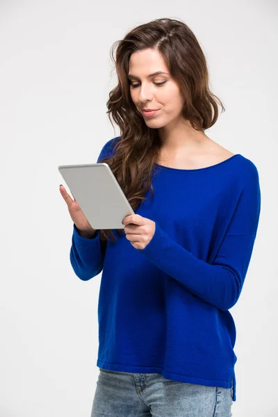 Sonriendo hermosa mujer joven de pie y utilizando la tableta — Foto de Stock