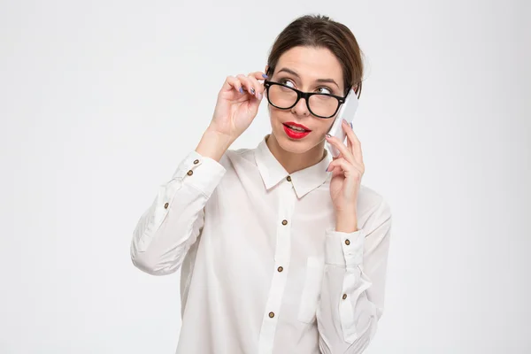 Thoughtful lovely businesswoman in glasses talking on cell phone — Stockfoto