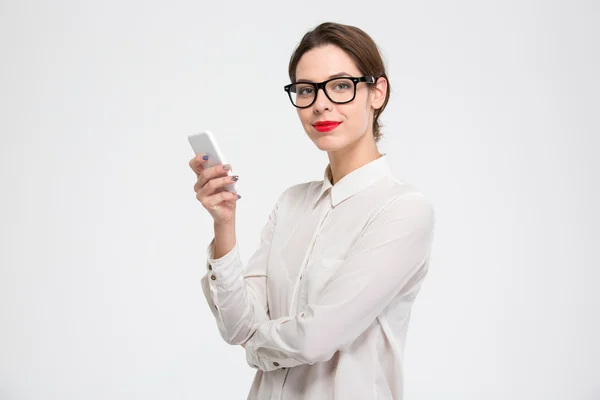 Heureuse jeune femme d'affaires confiante dans des lunettes utilisant un smartphone — Photo