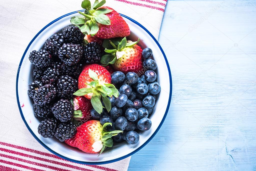 Rustic bowl full of forest summer berry fruits
