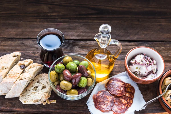 Planka med tapas, oliver och salami och olivolja — Stockfoto