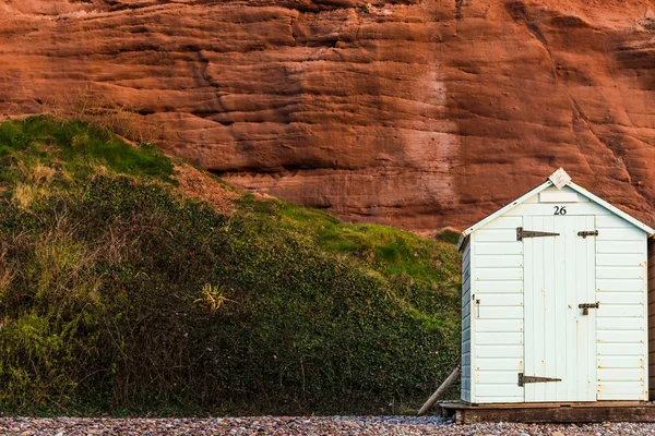 Ряды пляжных хижин в песочных цветах, красный каменный фон — стоковое фото