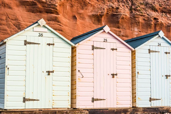 Beach hut row in pastel colors, red rock background — Stock Photo, Image