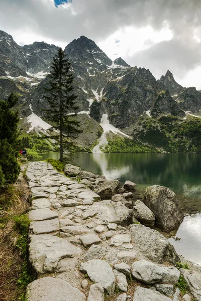 Caminhando julgamento por lago na alta gama de montanhas — Fotografia de Stock