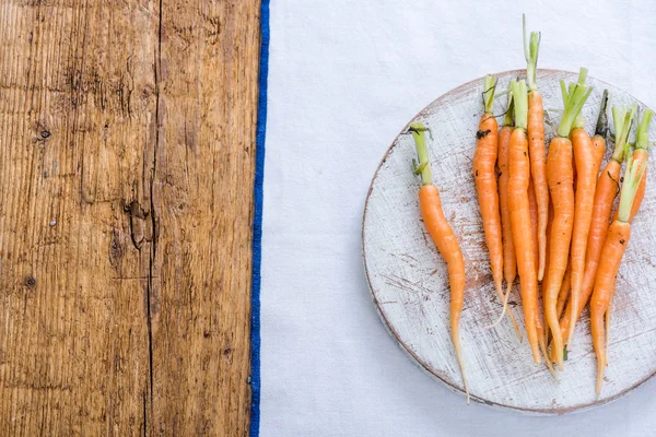 Jeunes carottes vibrantes sur une planche rustique — Photo