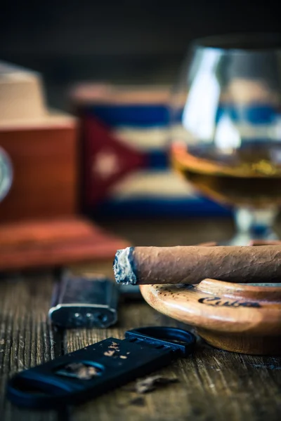 Smoking cuban cigar and humidor in background — Stock Photo, Image