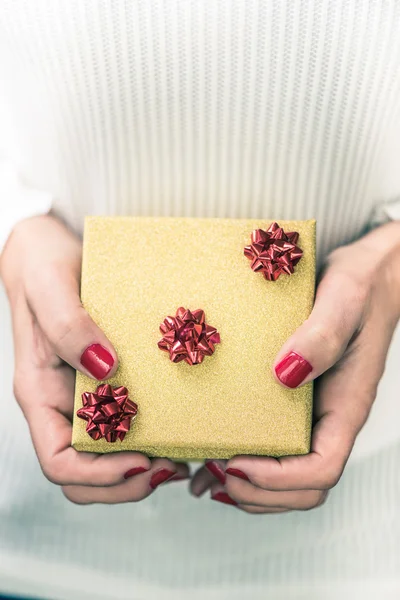 Руки женщины держат маленькую золотую шкатулку для подарков — стоковое фото