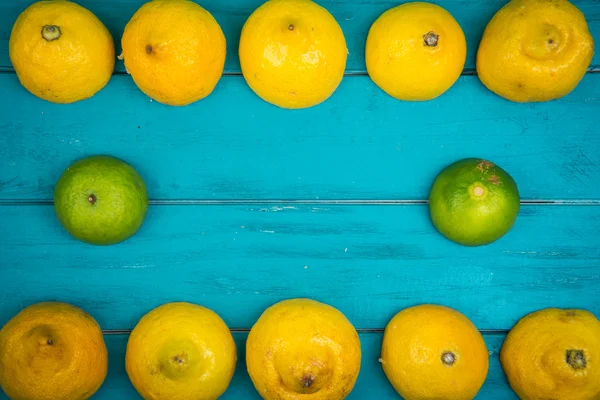 Fresh organic lemons and limes on wooden background — Stock Photo, Image
