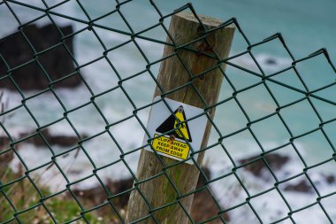 Safety warning sign on wooden post on cliff clipart
