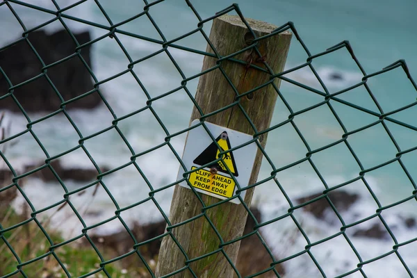 Safety warning sign on wooden post on cliff — Stock Photo, Image