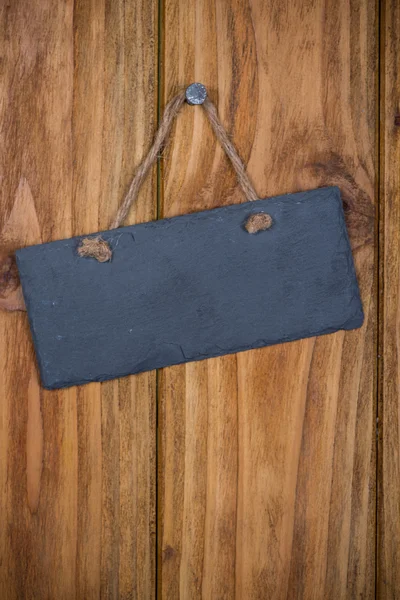 Placa de pedra com corda pendurada em backgroun de madeira — Fotografia de Stock