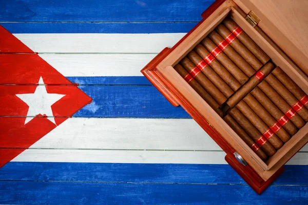 Humidor con puros sobre fondo de bandera cubana — Foto de Stock