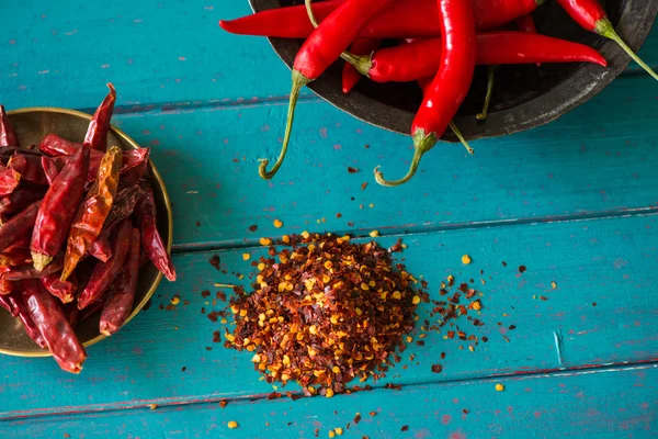 Fresh and dried hot chilli in bowl and seeds on table — Stock Photo, Image