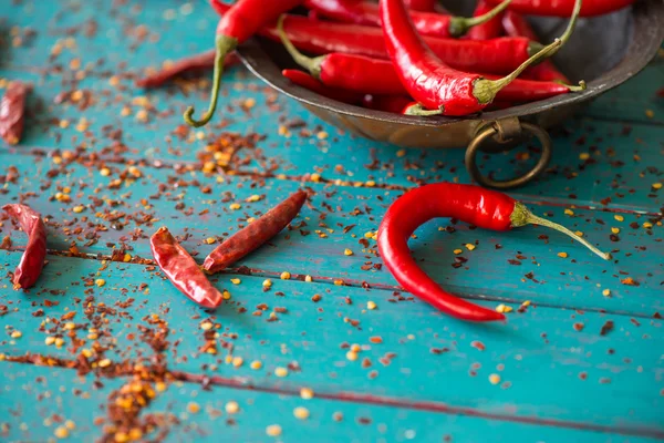 Vintage bowl with red pepers over dried chilli in background — Stock Photo, Image