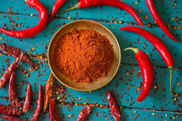 Chilli powder and fresh peppers on table — Stock Photo, Image