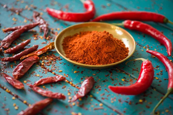 Chilli powder and fresh peppers on table — Stock Photo, Image