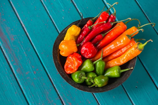 Vintage bowl with many chili peppers on wood — Stock Photo, Image