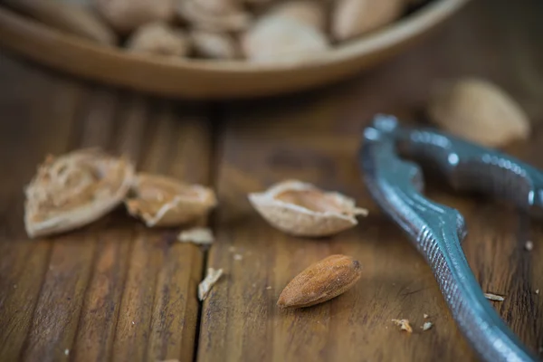 Whole almonds and nut crusher on table — Stock Photo, Image