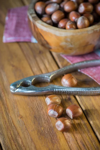Hazelnuts in bowl and nut cracker on cloth — Stock Photo, Image