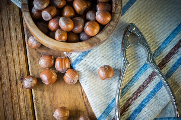 Top view over hazelnuts in bowl and nut cracker on cloth — Stock Photo, Image
